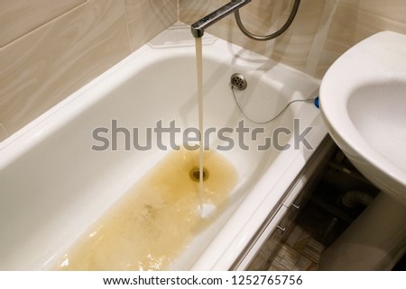 dirty, rusty water flows from the tap, unfit for drinking, water pipes Royalty-Free Stock Photo #1252765756