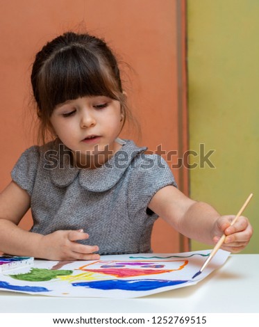 Little european girl painting at table indoors. Child drawing in her nursery at home