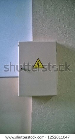 Texture and background of an old, but repaired or refurbished electric lizard with a shield in public buildings in the daytime. High Voltage Warning Sign.