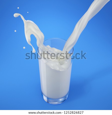 Fresh milk pouring into a glass with splash. viewed from above. On blue background.