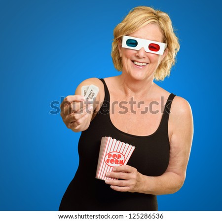 Happy Elderly Woman Wearing 3d Glasses Holding Popcorn And Ticket On Blue Background