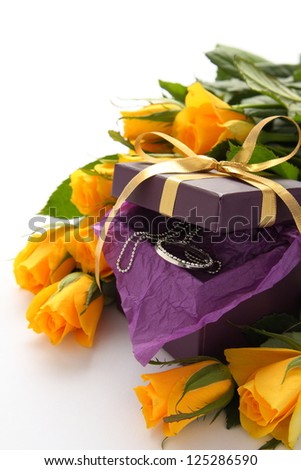 Yellow roses and purple gift box with jewelry on a white background