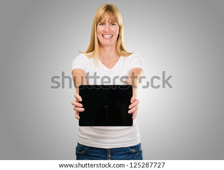 Happy Young Woman Holding Digital Tablet against a grey background
