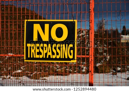 An image of a no trespassing sign posted to a chain link fence surrounding an excavation site.