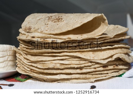 There are many corn tortillas on the table.