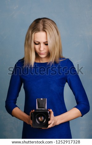 Beautiful Girl in vintage blue dress holding old medium format camera.