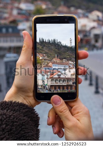 Woman hands take phone photo of Tbilisi city on Georgian. Maidan old district square on smartphone photography.