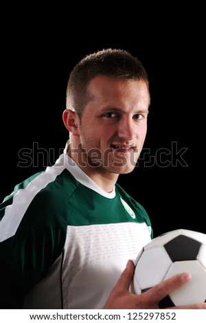 Soccer player holding a ball over black background