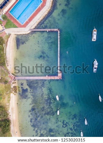Swimming pool near a river with jetty and sailing boats.