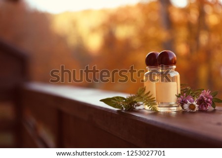Bottles with essential oil and ingredients on blurred background. Space for text