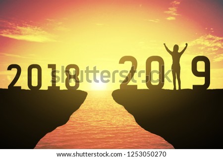 Silhouette of woman standing at 2019. 2018 and 2019 years. keep go on concept at 2019 over a beautiful sunset or sunrise at the sea. background for happy new years. success in 2019 years Royalty-Free Stock Photo #1253050270