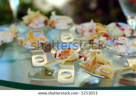 Gourmet banquet table featuring chicken and pasta canapÃ©s in individual serving spoons.