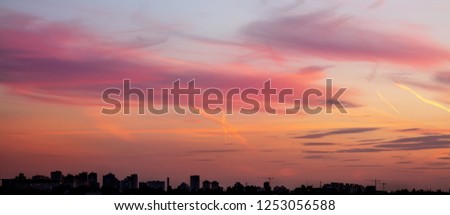 Cityscape with dramatic sky sunset. Silhouette of buildings aand cranes at construction site. Urban industrial city background