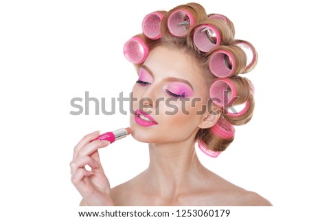 Beautiful woman with hair curlers with lipstick on white background