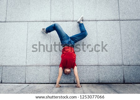 Woman hipster doing a handstand against wall
