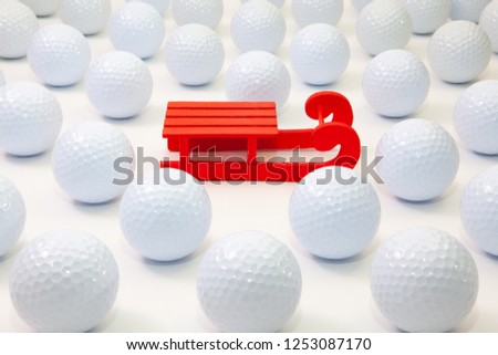 Pattern with white golf balls and Santa Claus red carriage on the table.