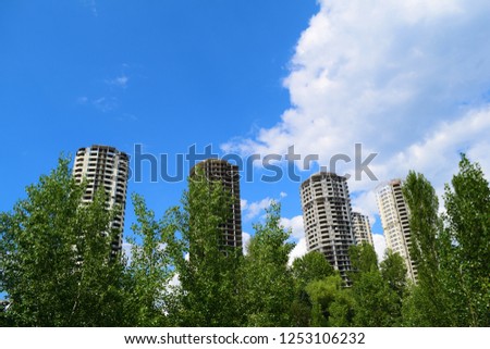 Bottom view through green trees on four multi-storey houses in the city
