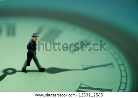 Miniature people : business man looking at watch and walking on the clock background, time business concept.