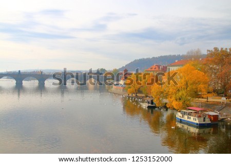 The photo was taken in Prague. The picture shows an autumn morning on the Vltava River. In the background is the Charles Bridge in the light fog.