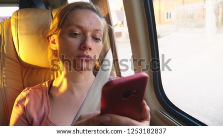 Tired woman rides the bus using her phone.