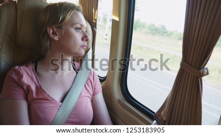Sad pensive girl riding bus and looking out window .