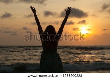 Silhouette of a girl against the sunset stretches to the sun