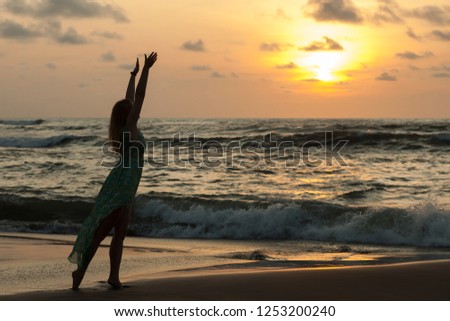 Silhouette of a girl against the sunset stretches to the sun