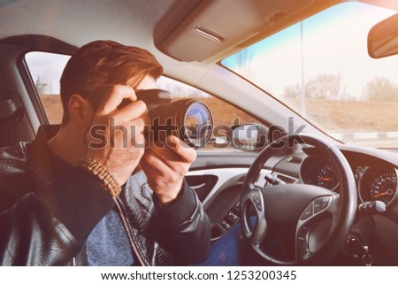 A man is taking pictures from a car window. Photographer traveler. The work of a private detective.