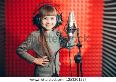 cheerful little kid with long brown hair recording her album . close up photo. preparation for the festival