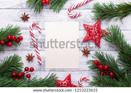 Christmas background. Fir branches, candy cane and gifts on a light wooden background. Cranberries, spices, holly berries. Flat lay, top view, copy space.