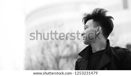 Black White photo of Asian young man outdoors posing at camera