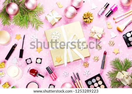Golden giftbox, make up cosmetics and Christmas decorations on pink background, copy space