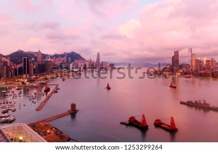 Scenery of Hong Kong at dawn, with a city skyline of modern skyscrapers on Kowloon peninsula & in Hongkong Island by Victoria Harbour and ships navigating in the seaport under beautiful twilight sky