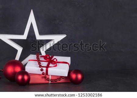 Christmas gifts, white star, red balls, garland on gray concrete background. Greeting card concept. Close-up, copy space, layout design