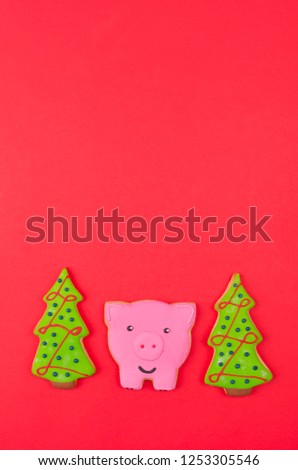 Cookies in the shape of a pig and a Christmas tree on red background. Vertical compozition.