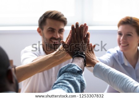 Happy diverse businesspeople giving high five, close up focus on people hands. Friendly multiracial company staff stacked their palms together symbol of friendship and good relations between coworkers Royalty-Free Stock Photo #1253307832