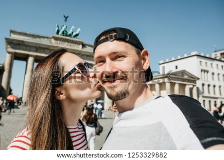 Young beautiful couple making selfie against the background of the Brandenburg Gate in Berlin in Germany. The girl kisses the guy.