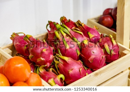 Pitaya or the fruit of the dragon lie in a wooden box in the store on the shelf.
