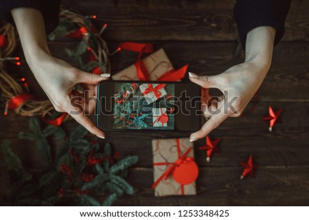 Hands with smart phone pictures of Christmas decoration. Young woman, blogger preparing for the holiday at the home and is making photo at smartphone. Instagram blogger workshop concept. Toned image.