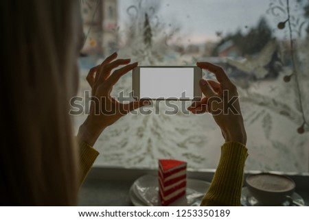 Person is taking photo with a smartphone. Close-up image of female hands using smartphone on coffee shop, searching or social networks concept, hipster girl sends an image to her friends.