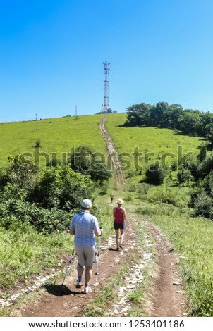 Tourists walk along the road to communications tower on top of a hill