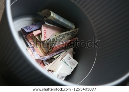 A plastic bin filled with money from around the world. This image can be used to represent the concept of money wasting. 
