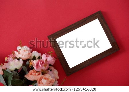 Mock-up wooden photo frame with space for text or picture on red background and flower