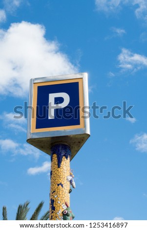Giant blue P parking sign set against a blue and clouded sky with copy space.