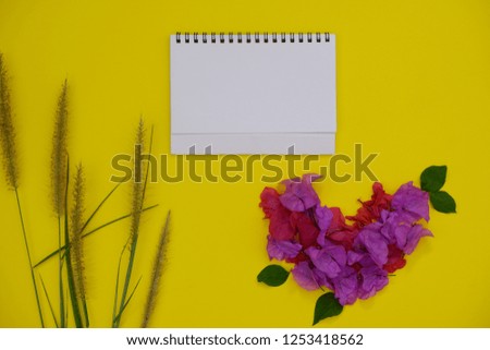 Mock-up white paper with space for text or picture on yellow background and tropical flowers