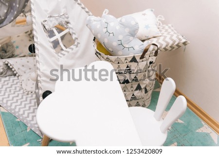 Cozy children's room in white, gray and blue colors.Vivam for sleeping bag for storing toys, Desk and puff chair with ears of a rabbit
