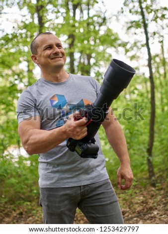 Professional nature photographer holding a camera with a big telephoto lens