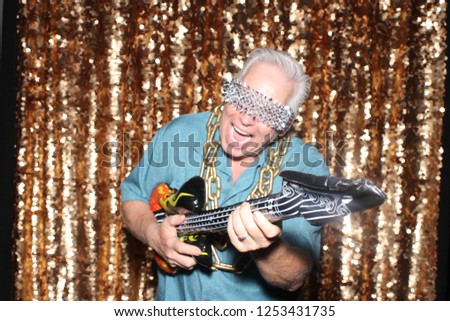 Photo Booth. A man smiles and poses with an inflatable Guitar in a Photo Booth. Photo Booth pictures. 