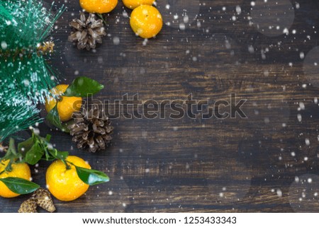 Mandarin fruits, Christmas tree branches and cones on a rustic background in the snow. Christmas holidays