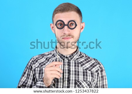 Portrait of young man with paper glasses on blue background